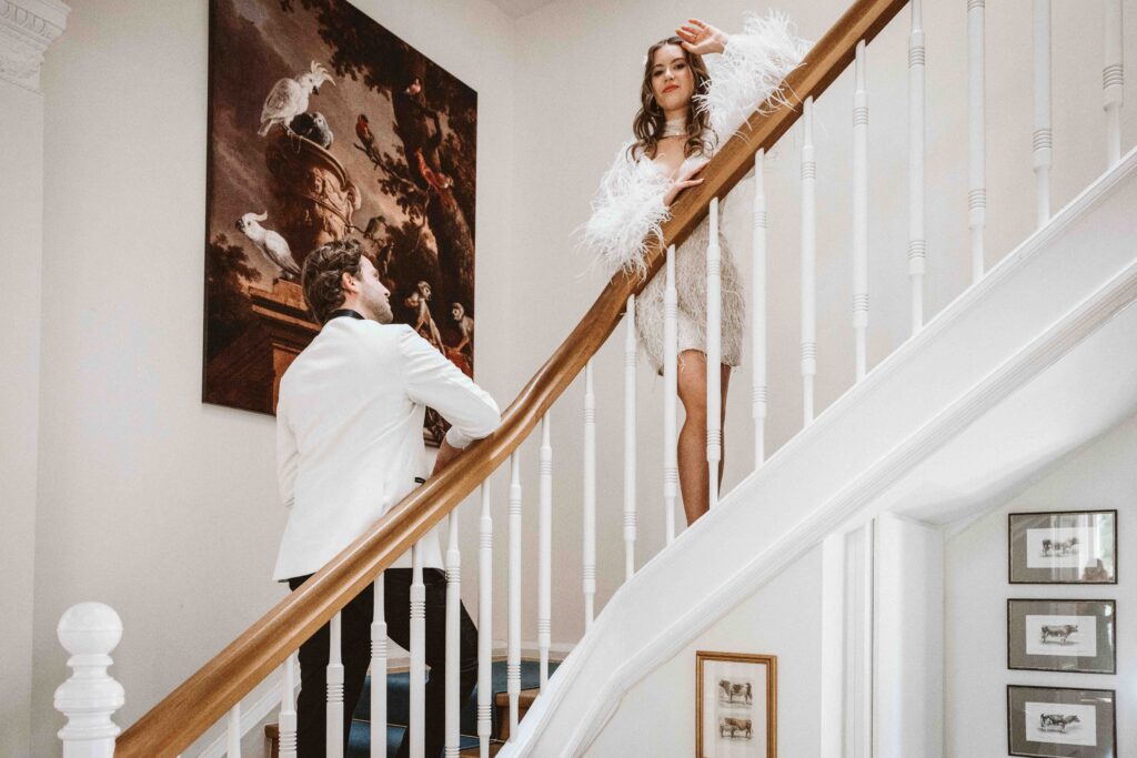 Braut blickt auf der geschwungenen Treppe der Villa Bodinus selbstbewusst in die Kamera.